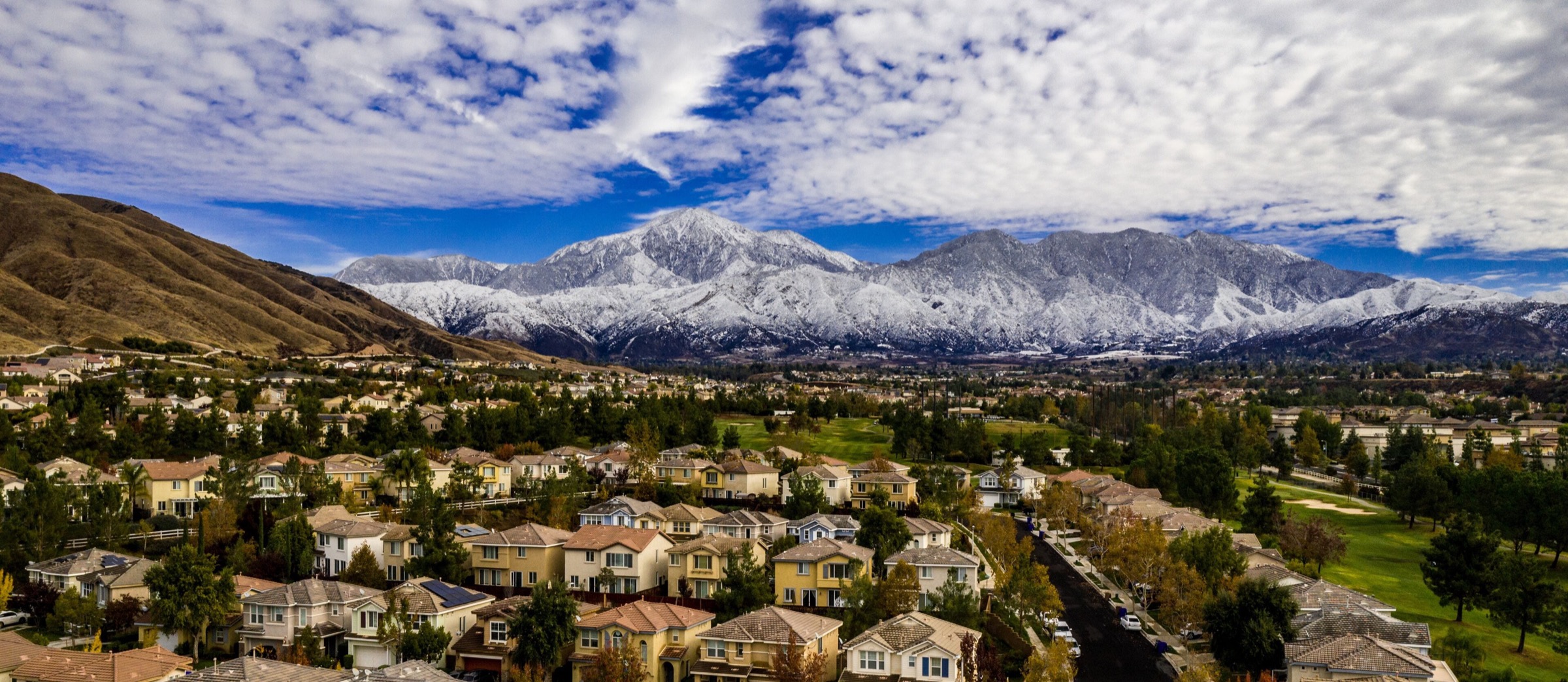 Yucaipa neighborhoods seen from above, with the snow-capped San Bernardino Mountains behind the valley