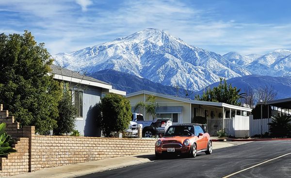 A Yucaipa residential street with the snow-capped San Bernardino Mountains rising behind the rooftops