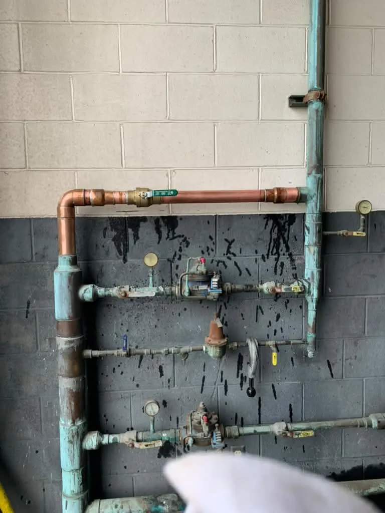 Copper and galvanized manifold with gauges mounted on a block wall in a commercial space