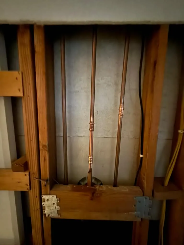 Fresh copper repipe risers in an opened stud bay, gas flex alongside