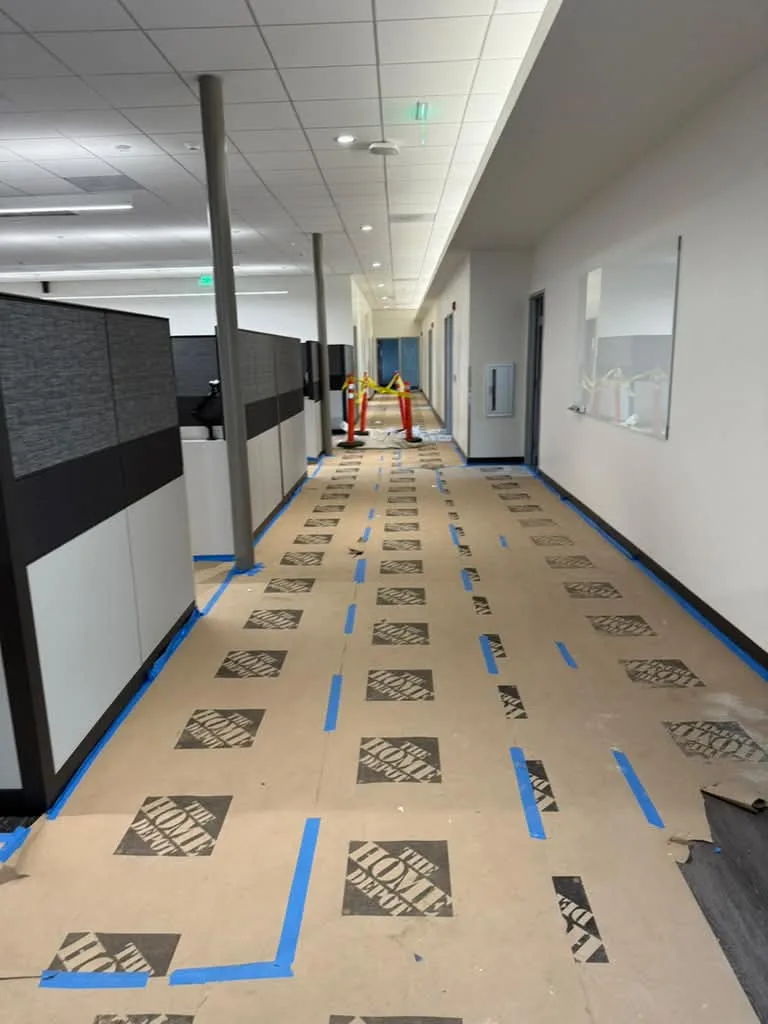 Office corridor with floor paper, tape lines and safety cones during a commercial job